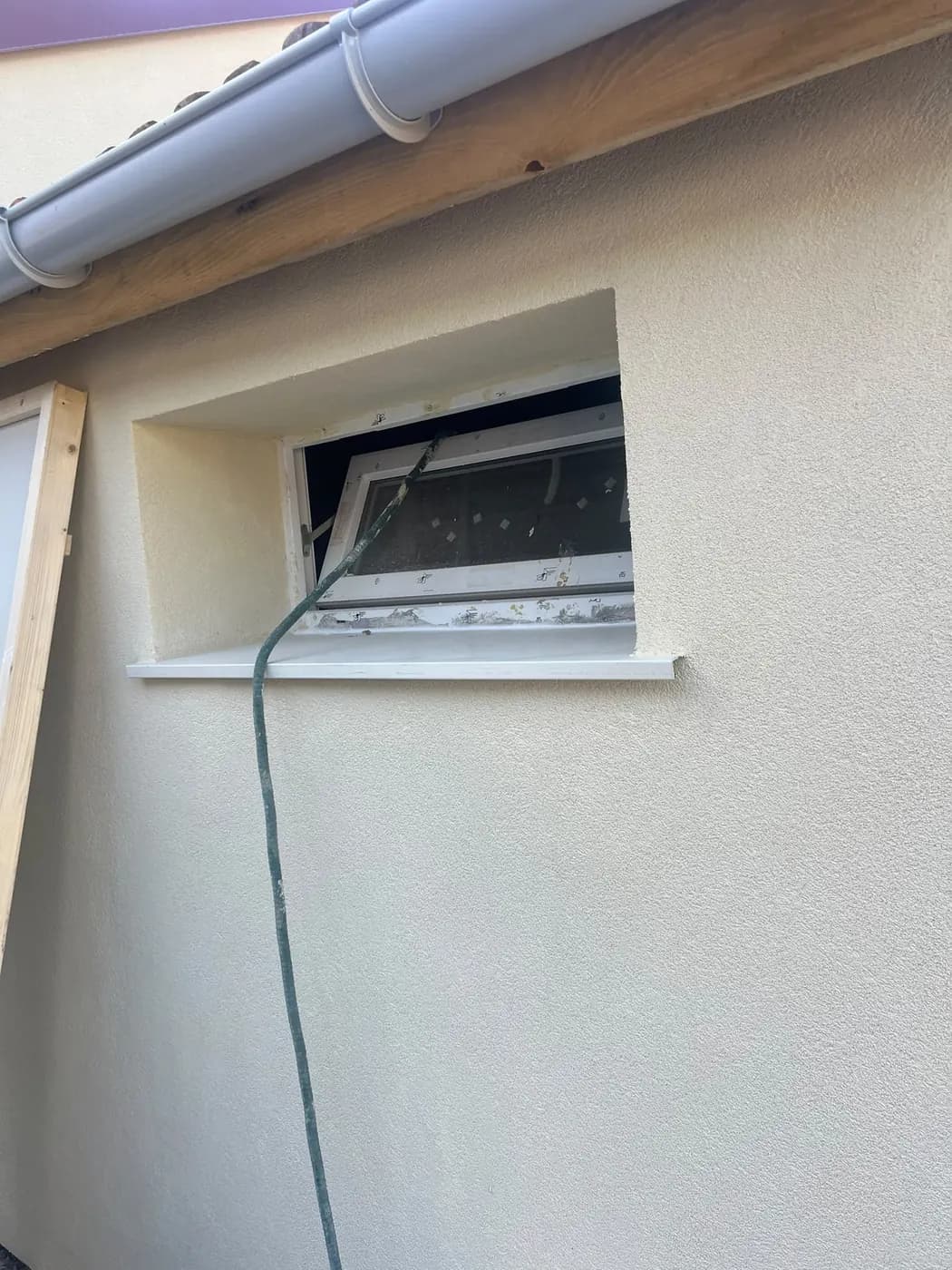 Finition soignée de l'enduit sur ouverture basse et soupirail de maison rénovée