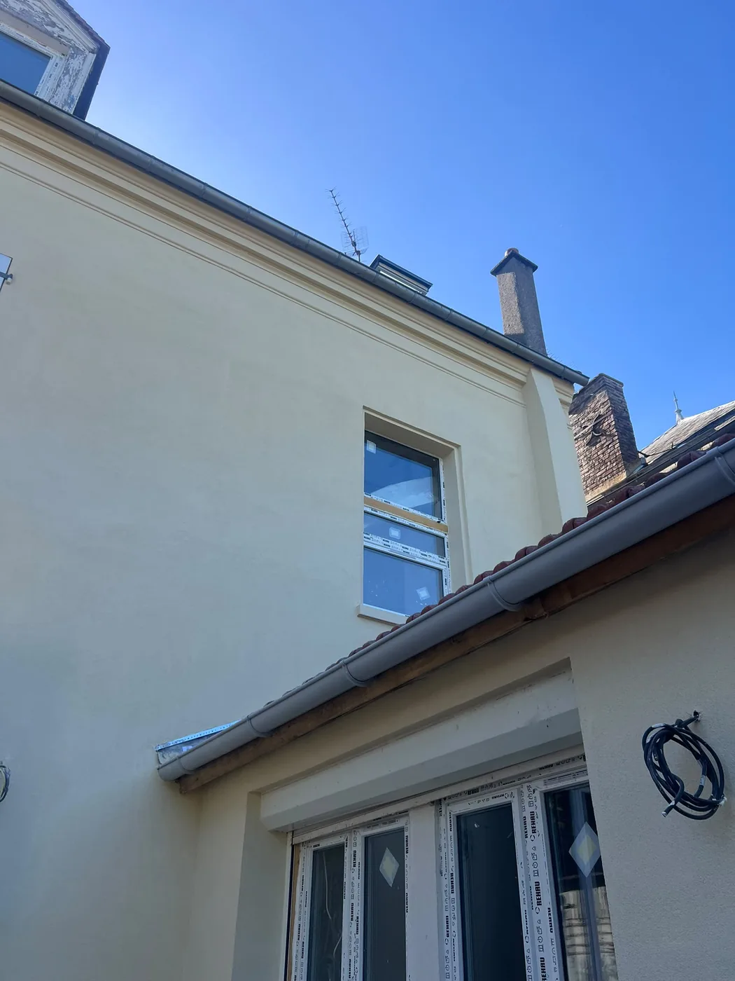 Façade d'étage rénovée avec enduit beige et fenêtre isolante neuve à Us