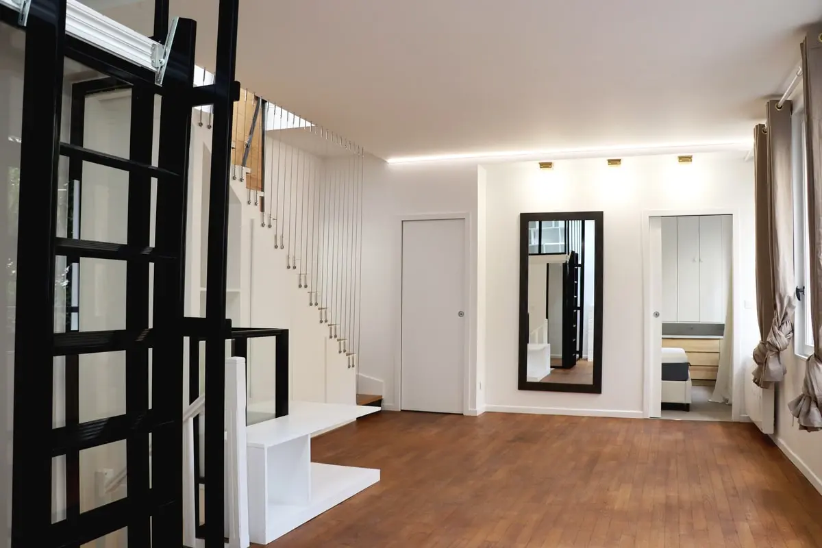 Pièce de vie rénovée avec parquet et claustra noir