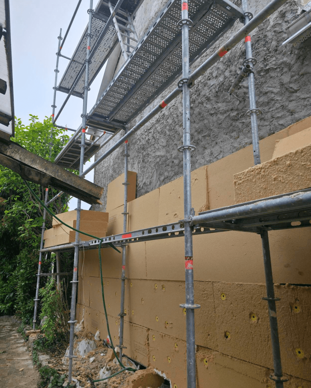 Chantier d'isolation extérieure KS RENOV dans le Val-d'Oise : pose de panneaux isolants sur échafaudage pour supprimer les ponts thermiques.